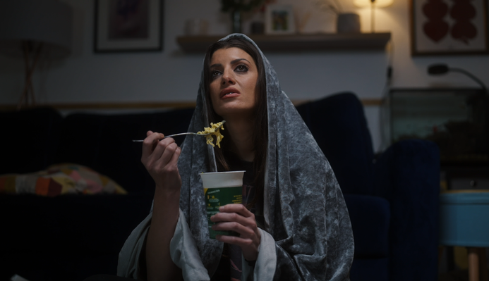 Natasha eating a pot noodle, wrapped in a blanket