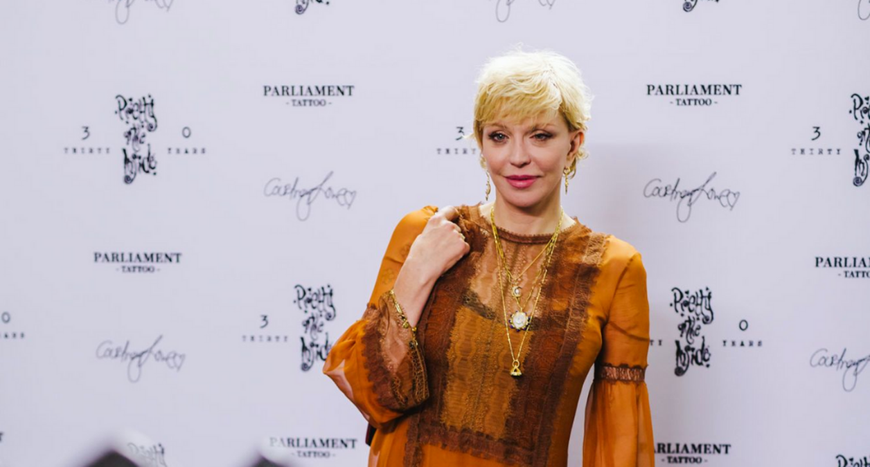 Courtney Love at the art auction, wearing an orange dress