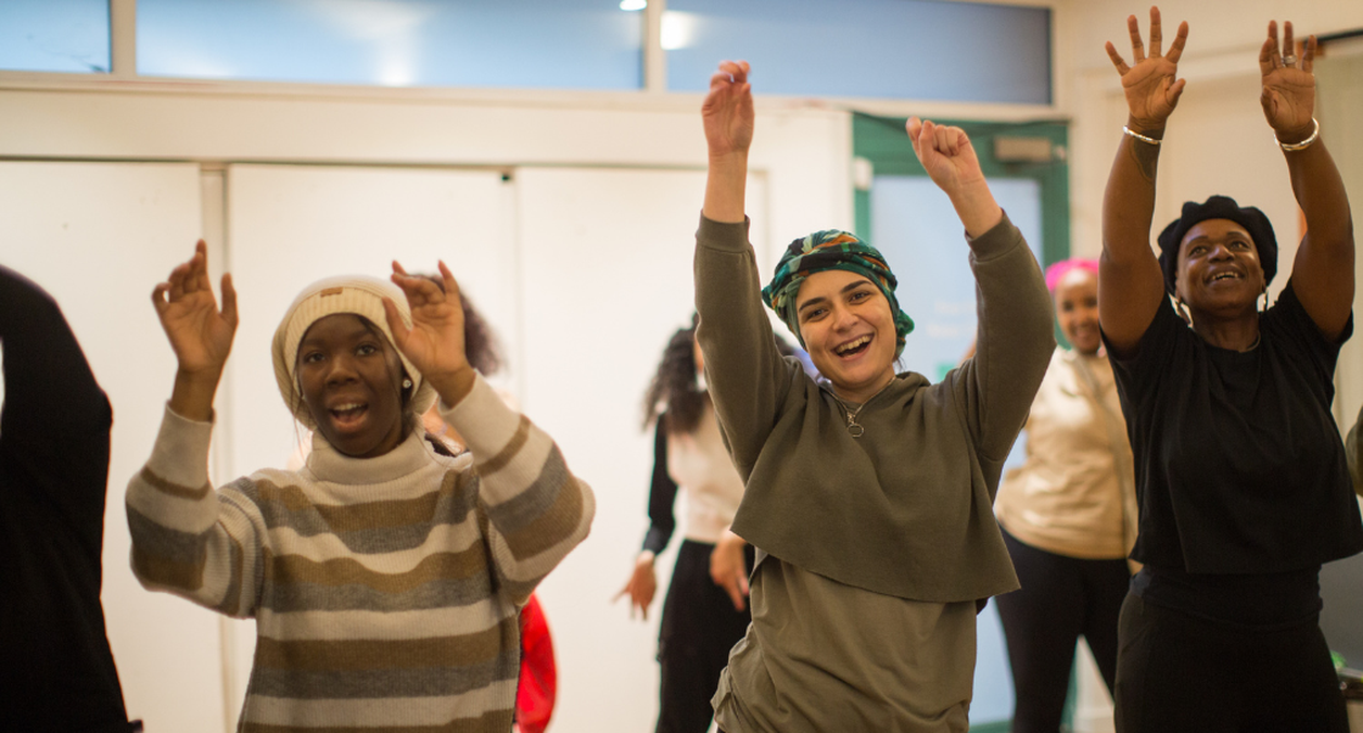 Members smiling and lifting their arms in the air at Clean Break