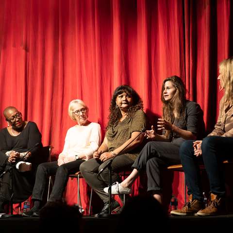 clean break writers sat on a stage in front on a red curtain