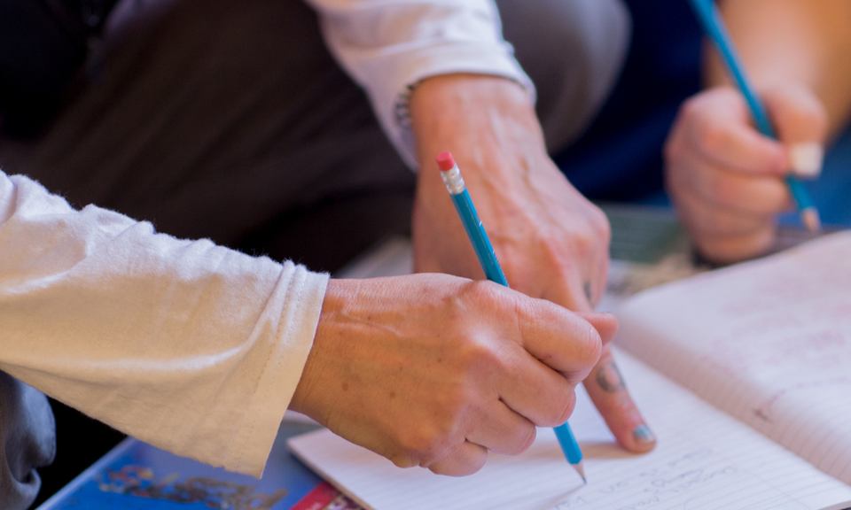 The hands of two people writing together.