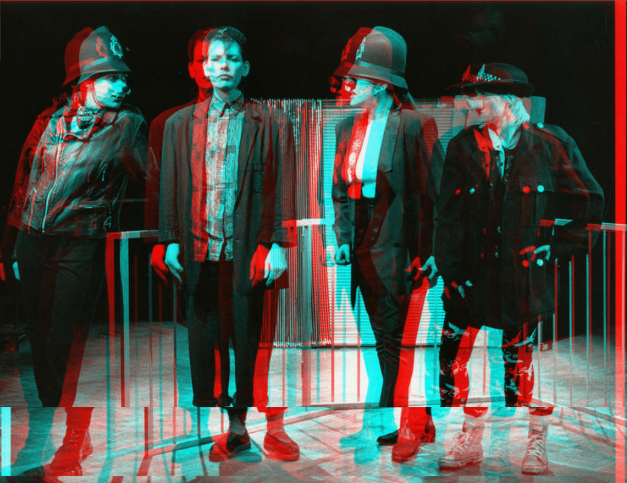 a black and white photo with a distorted affect over the top of a Clean Break production from the 80s, there are four women on stage, three are in police hats with pig noses on.