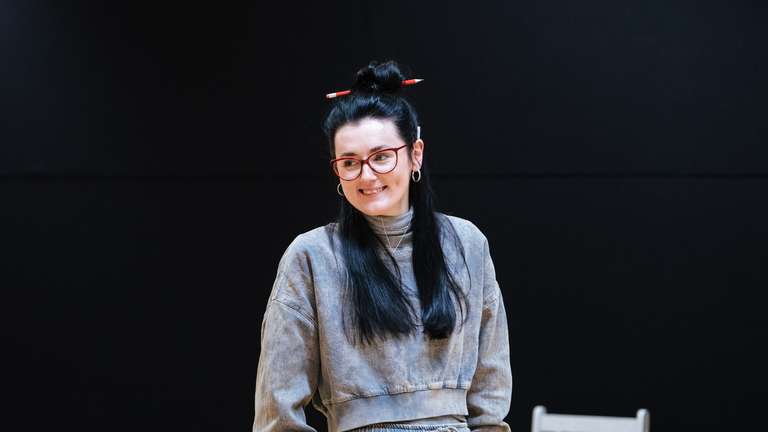 Posy in rehearsals for Dixon and Daughters, she is wearing a grey tracksuit and smiling