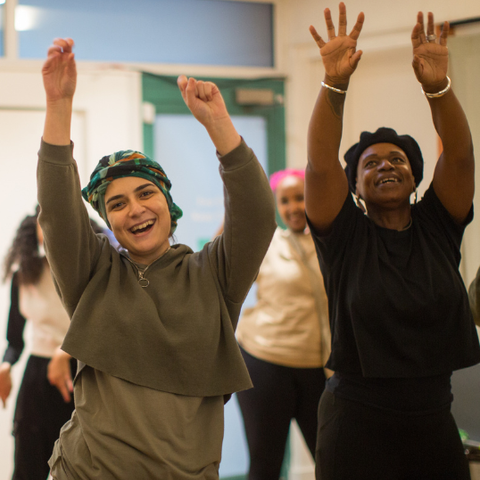 Members smiling and lifting their arms in the air at Clean Break