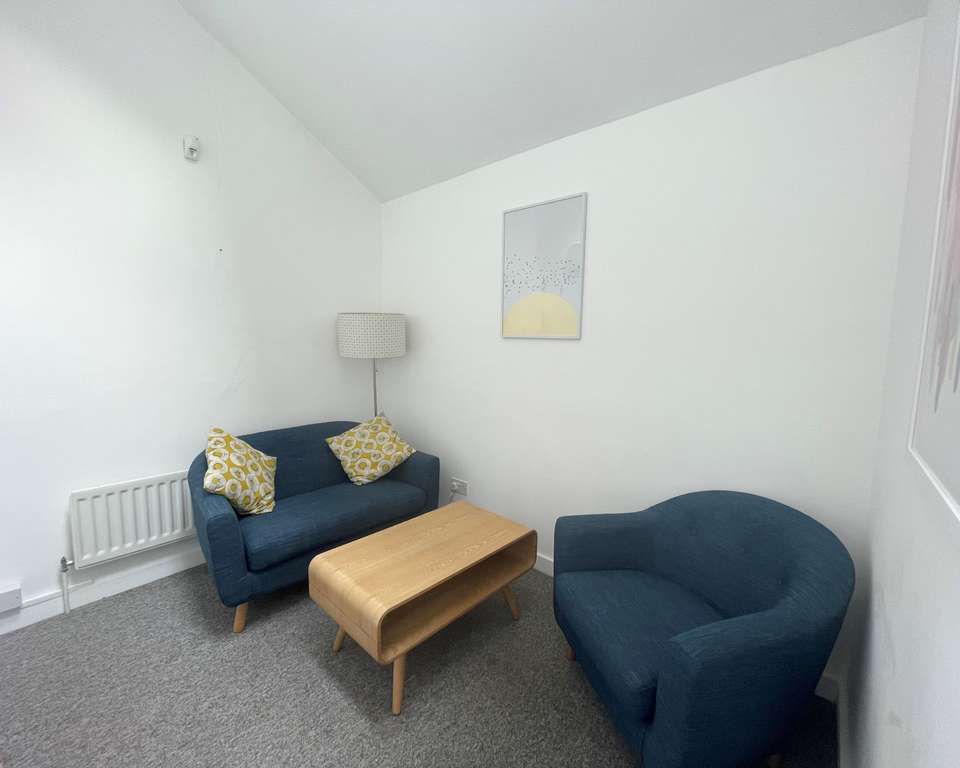 a photo of a small meeting room with two arm chairs and a coffee table, with white walls