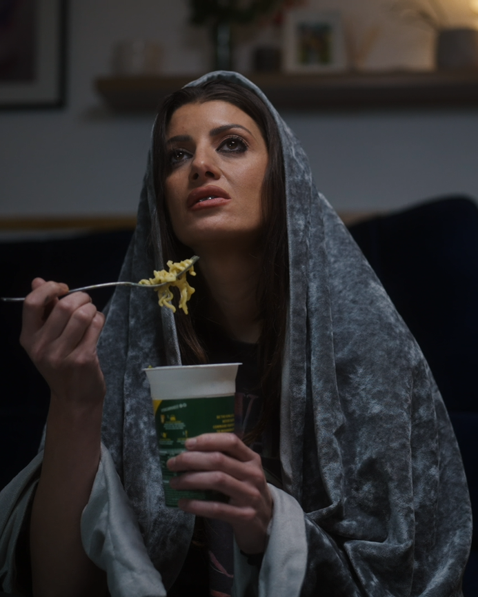 Natasha eating a pot noodle, wrapped in a blanket