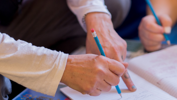 The hands of two people writing together.