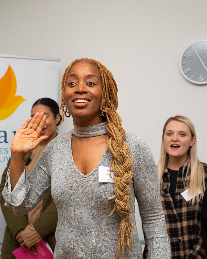 A photo of JB Rose at the opening of a new women's centre, delivering a signing workshop with Clean Break Members