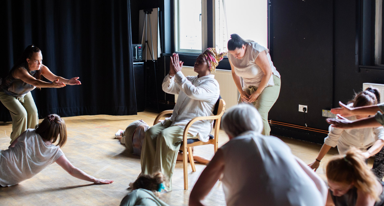 A group of women perform site-specific dance piece A Wondering Willow Dreams in the black-box studio of Clean Break's building.