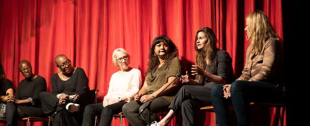 clean break writers sat on a stage in front on a red curtain