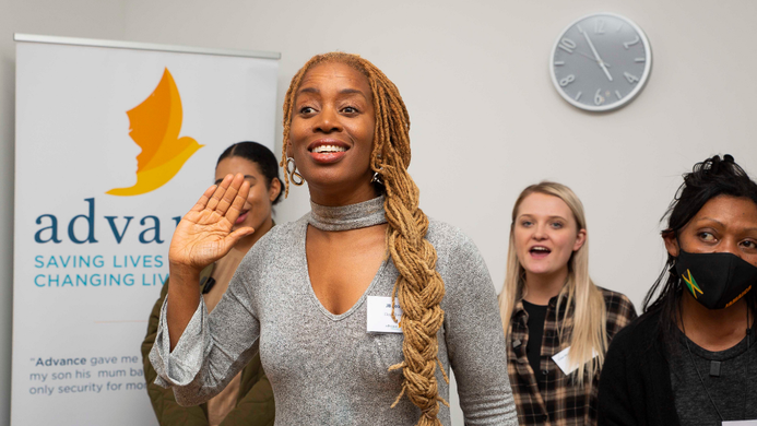 A photo of JB Rose at the opening of a new women's centre, delivering a signing workshop with Clean Break Members