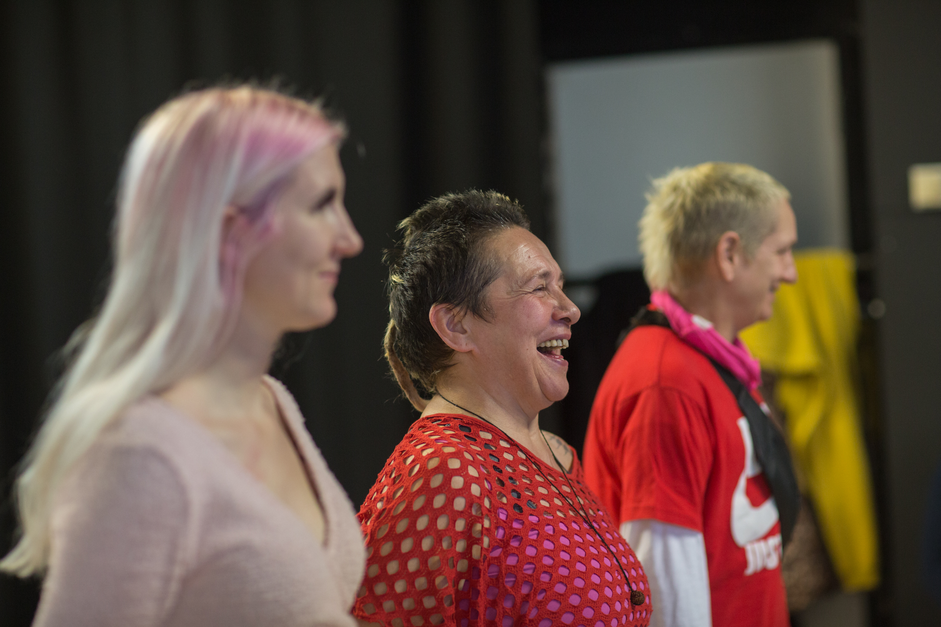 a photo of three memebers standing in a row, they are smiling and laughing