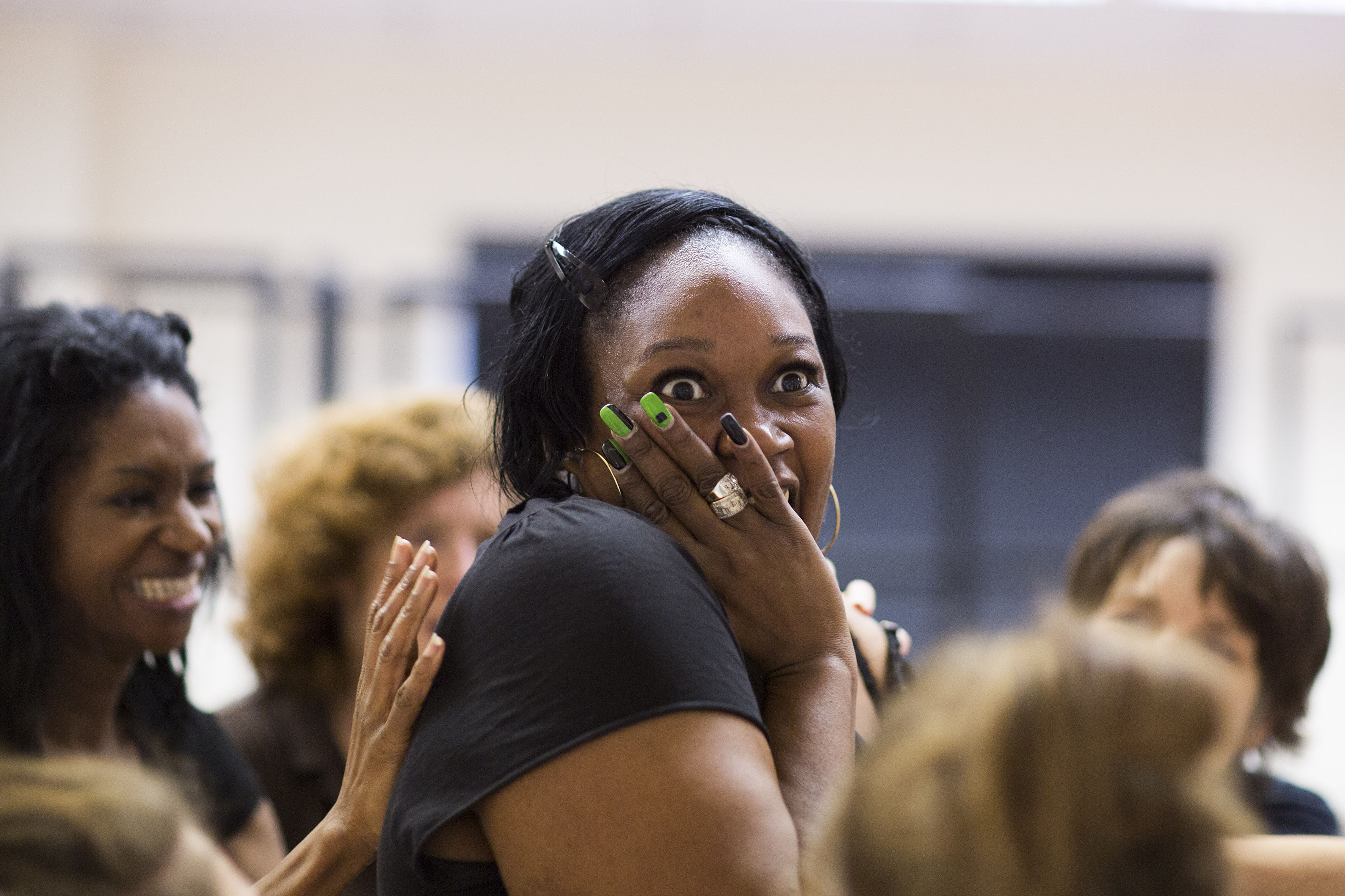 Jennifer Joseph in rehearsals for the Donmar Trilogy. She is laughing and has her hand over her mouth. She is wear a black top and has black and bright green decorative nails.