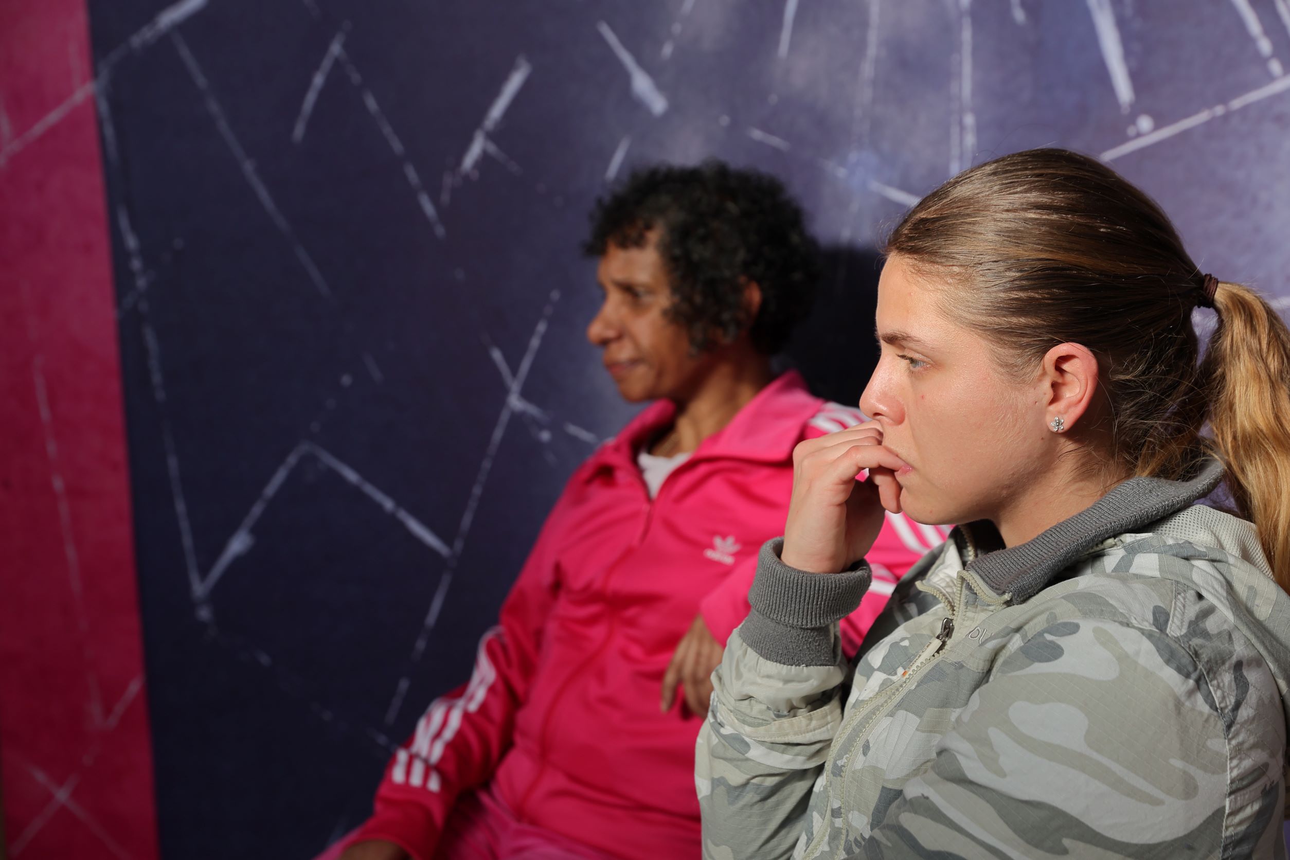 a photo of a performance of Catch. two women are sitting on chairs, one is looking worried and biting her nails.